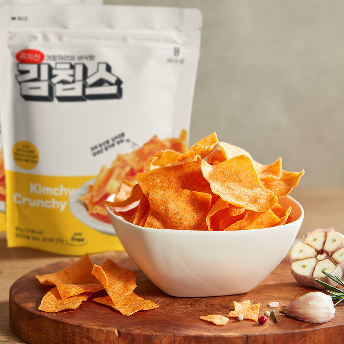 White bowl of crunchy orange kimchi chips beside a chips bag