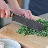 Vegetable knife in use, dark blade with wooden handle