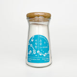 Glass salt container with white salt, blue label, and cork lid.