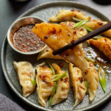 Plate of dumplings topped with chili crisp sauce and sesame seeds