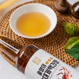 Soy sauce bottle lying down, crab label on the front, amber sauce in glass