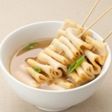 Noodle bowl with light sauce and crab-themed garnish, chopsticks resting on top