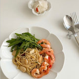 White flower-shaped plate with pasta and shrimp