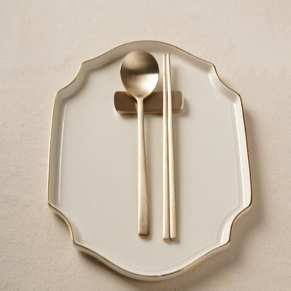 Bronze spoon and chopsticks on a decorative white plate