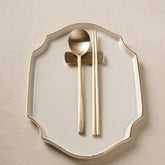 Bronze-tone spoon and chopstick set on white plate