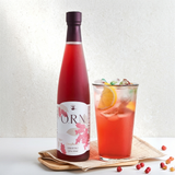 Omija extract bottle with dark cap and glass of red omija drink on tray