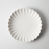 White fluted flower-shaped plate with petal-like ridges