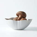 White round flower-burst bowl holding brown mushrooms