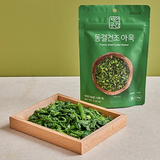 Freeze-dried curled mallow greens namul in a green stand-up pouch with wooden box