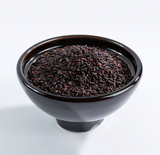 Organic germinated black rice in a dark bowl, loose uncooked grains