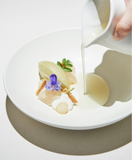 White pasta bowl being filled with food and sauce