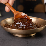 Spoonful of dark apple ginger extract paste in a metal bowl
