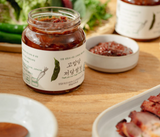 Ssamjang jar with red-brown paste, served with small bowls of sauce.