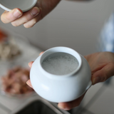 Mini white ceramic bowl with open top, held in hands