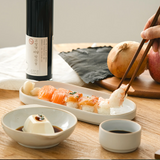 Soy sauce bottle with white label beside bowls and chopsticks