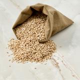 Bag of pale sesame seeds with scattered seeds on a light surface