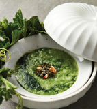 Maesaengi green soup in bowl with leafy greens and white spoon