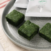 Green herbal paste cubes in a metal tray, textured surface