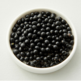 Mini black soybeans in a white bowl, whole dark beans