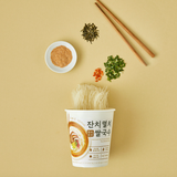 Rice cup noodles with chopsticks and seasoning ingredients around a paper cup