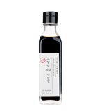 Soy sauce bottle with black cap and white label filled with dark brown liquid