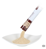 Natural seafood stock powder poured from a sachet into a white scoop.