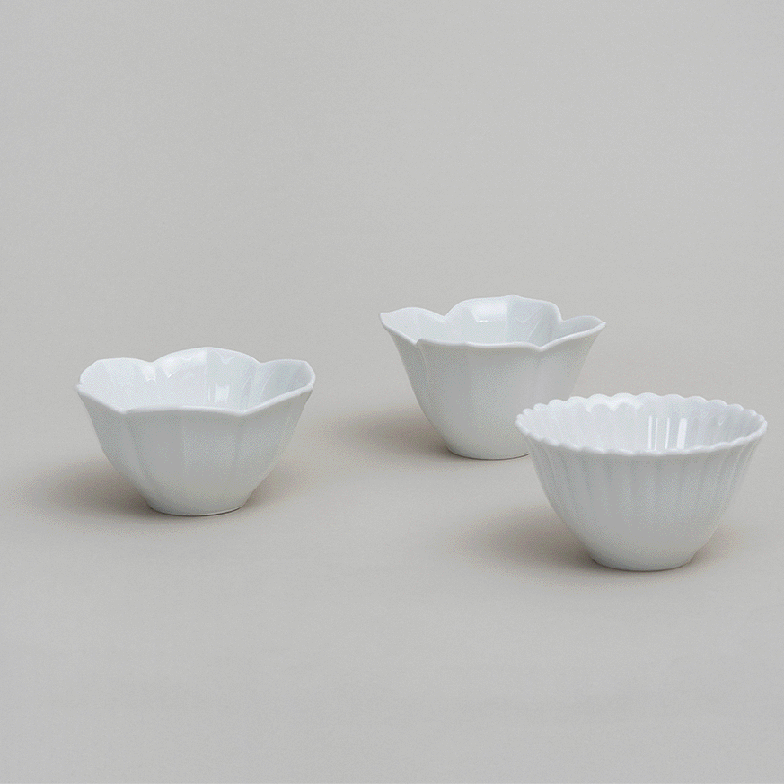 Three white tiny flower bowls in different petal styles with scalloped edges