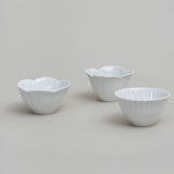 Three white tiny flower bowls in different petal styles with scalloped edges