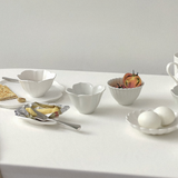White tiny flower bowls with scalloped edges, arranged for a table setting