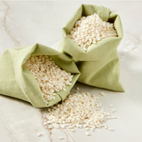 Organic rice flour kernels in open green cloth bags, with loose white grains