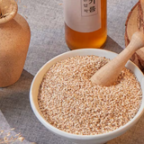 Roasted sesame seeds in a white bowl with wooden scoop
