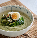 Bowl of green noodles with sliced greens and a halved egg