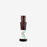 Small sesame oil bottle with amber glass, white label, and green accents; cap