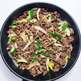 Bulgogi sauce bowl of cooked beef with sliced onions and green scallions