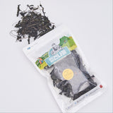 Dried sea greens pouch with dark leaf strips scattered beside it