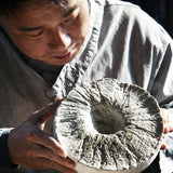 Fruit vinegar serving: person holding and adjusting a textured round flatbread
