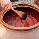 Ssamjang paste in a clay bowl, spread with a wooden spoon