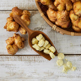Freeze-dried minced ginger tablets in a wooden spoon with ginger roots nearby