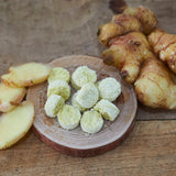 Freeze-dried minced ginger tablets with sliced ginger on a wooden dish