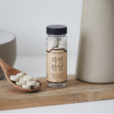 Natural seafood stock tablets bottle beside wooden spoon of white tablets