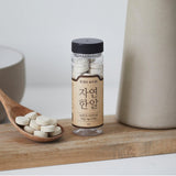 Natural seafood stock tablets bottle beside wooden spoon of white tablets