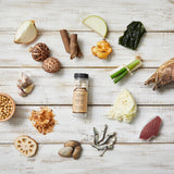 Natural seafood stock tablets bottle centered among assorted vegetables and seafood