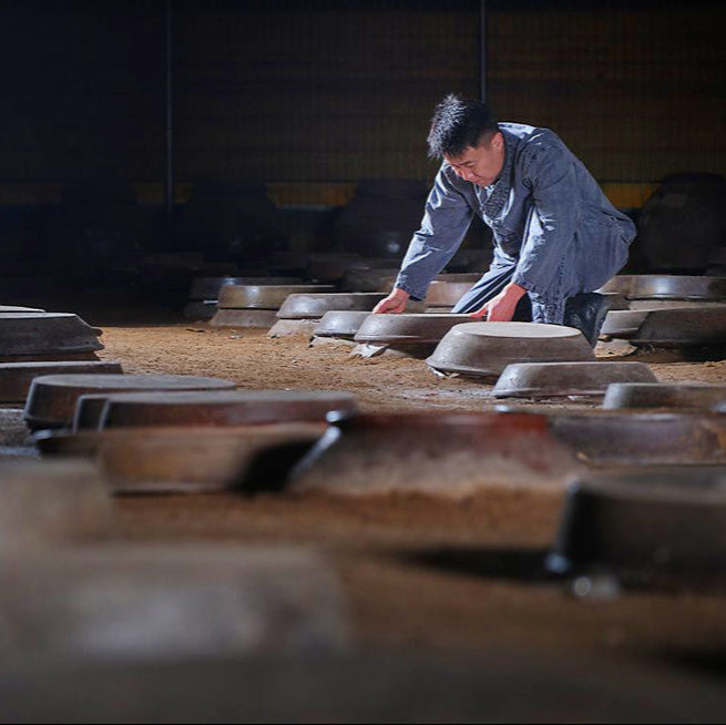 Fruit vinegar production: worker tending fermentation containers
