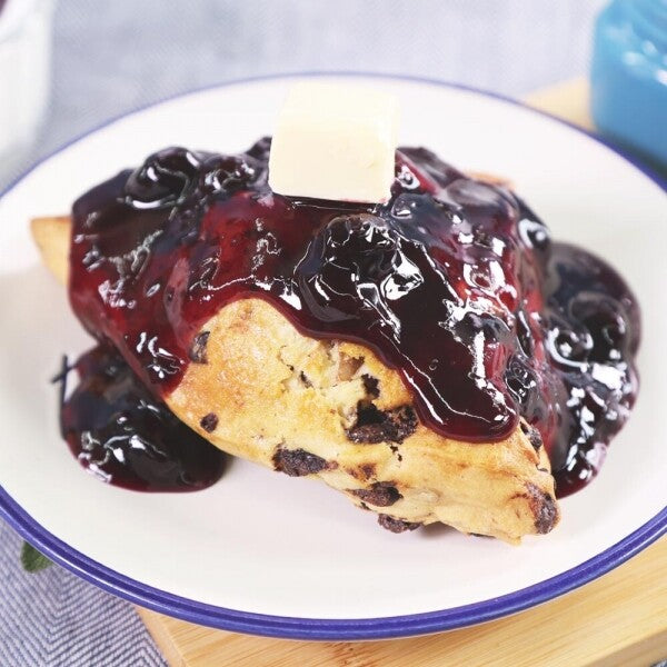 Dessert slice with dark berry jam sauce and whole blueberries