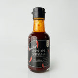 Hot buldak sauce bottle with dark brown sauce, black cap, dark label marked 'Real hot'