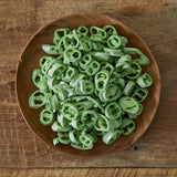Sliced chili peppers in a wooden bowl, green rings and pieces