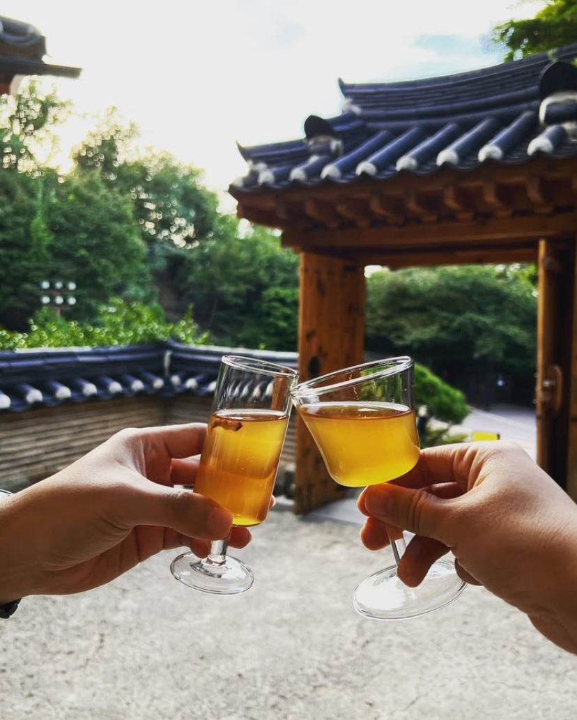Organic plum extract drink in two small amber glasses held by hands