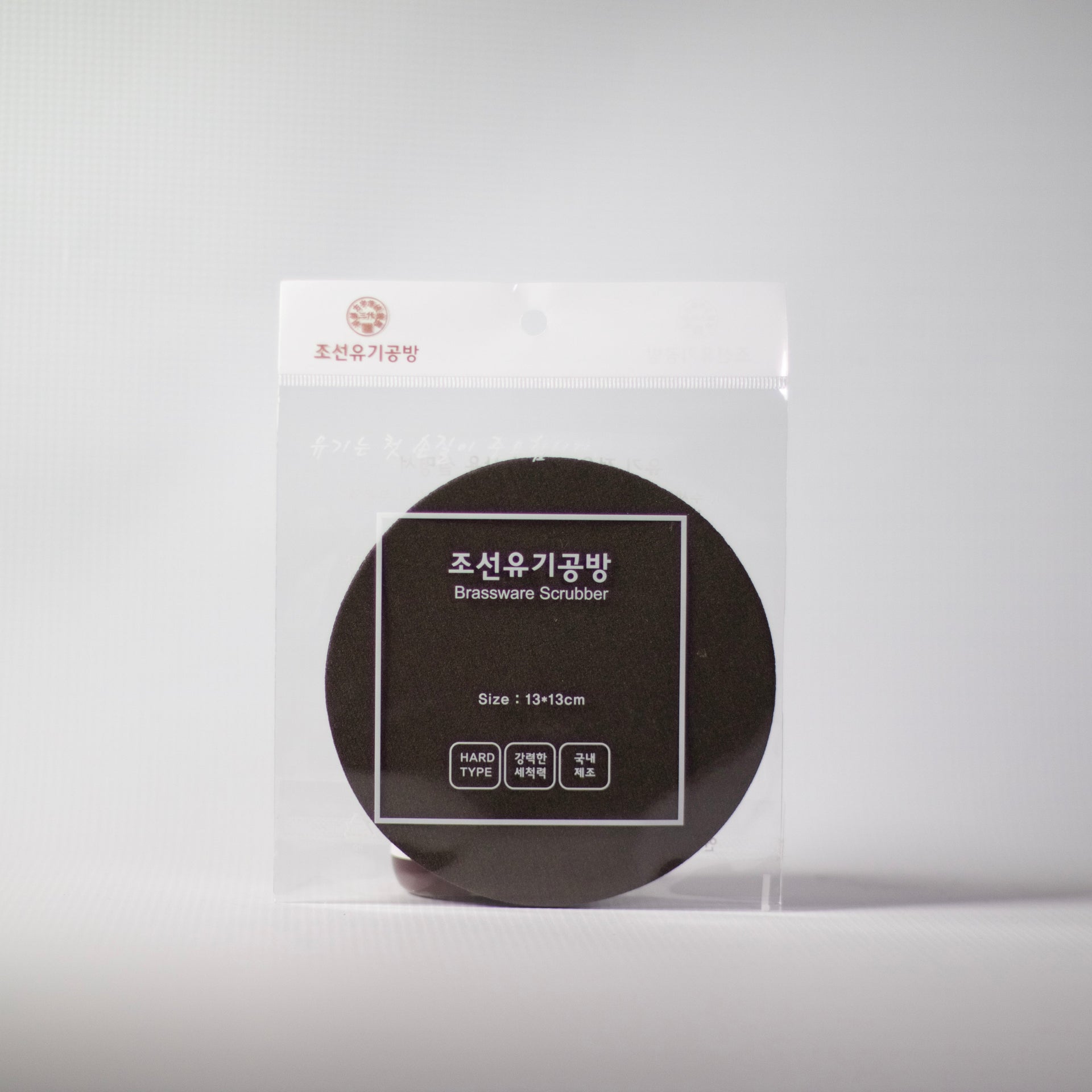 Round dark Bronzeware scrub sponge in clear plastic package