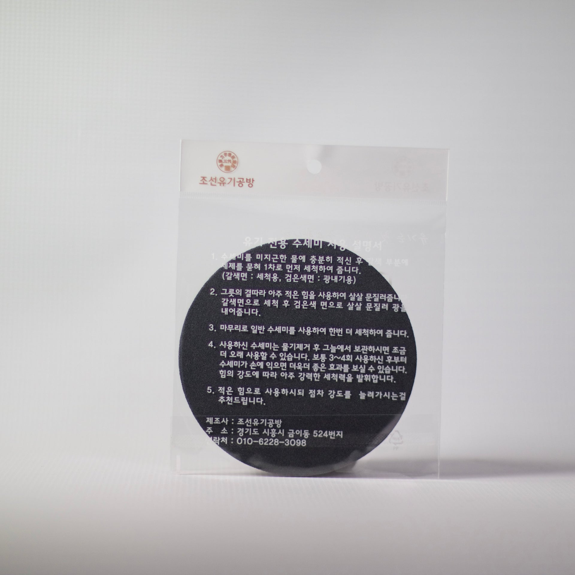 Round dark Bronzeware scrub sponge in clear plastic wrapper with label