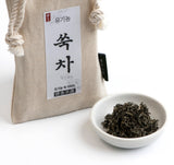 Organic mugwort tea pouch close-up with printed label and bowl of dried leaves